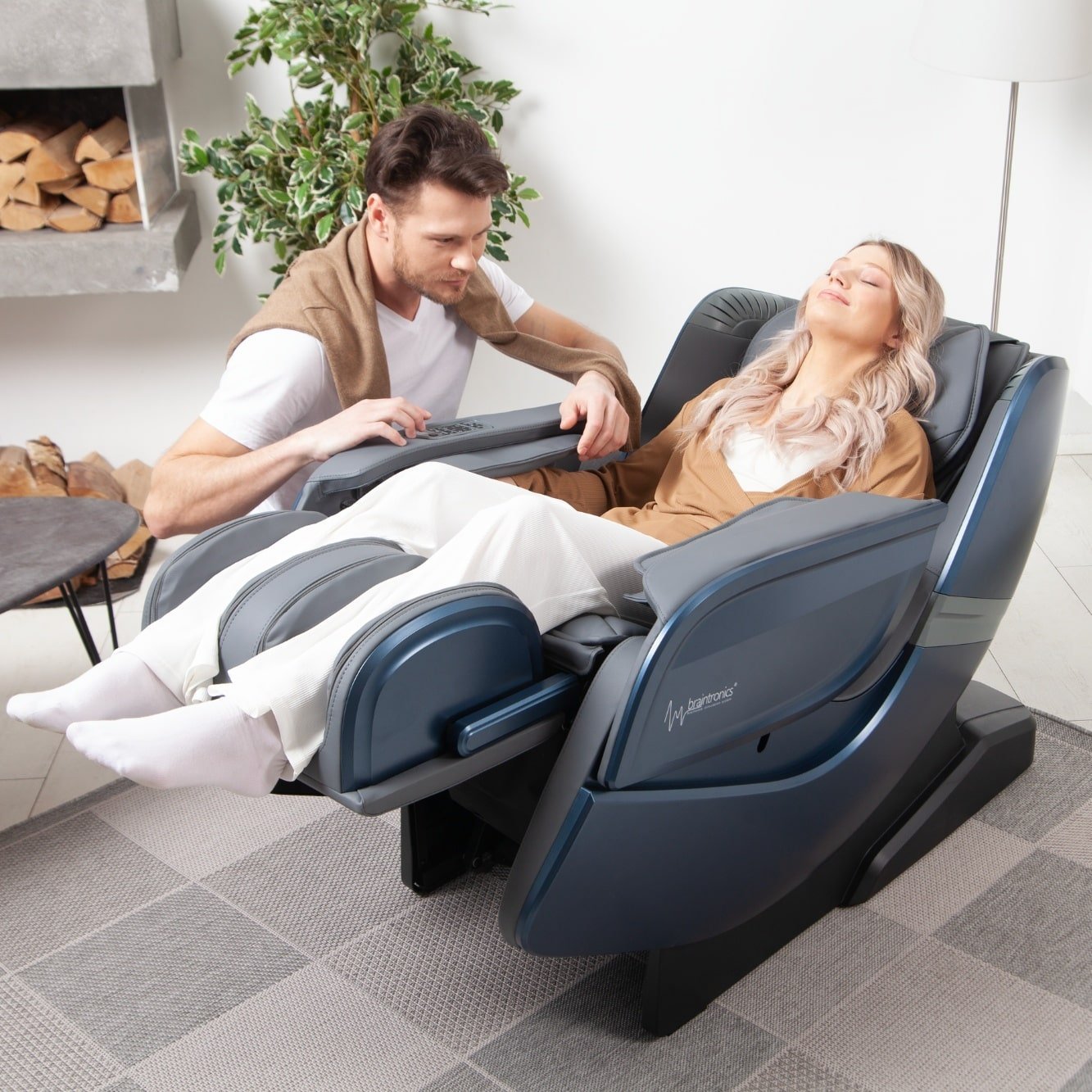 vrouw ligt in massagestoel Ecosonic - Blauw met man ernaast hurkend