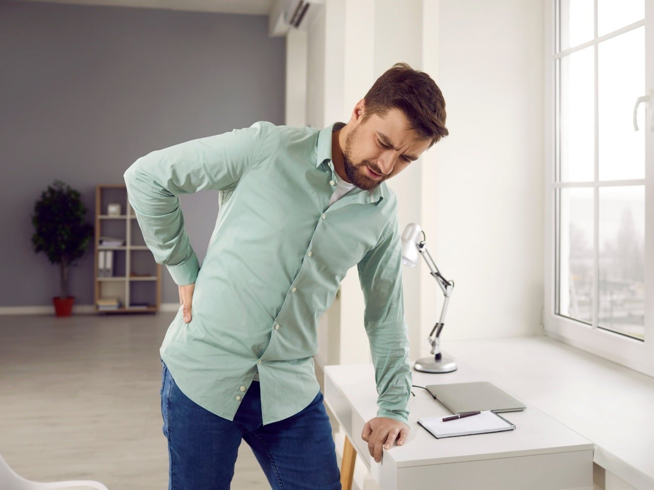 Mann im grünen Hemd macht Hexenschuss-Übungen
