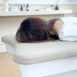 Persoon in buikligging op de Japanse Headspa Pro met het hoofd op het steunkussen