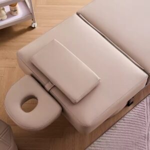 Detailopname van het beige behandelbed met gezichtsopening en steunkussen